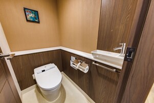 Un baño pequeño y moderno con inodoro, lavamanos y un mueble de madera.