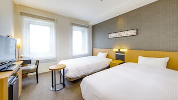 Una habitación de hotel con dos camas, un escritorio, una silla, un televisor y una mesita.