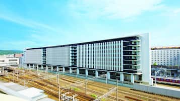 A modern train station with multiple tracks and a large building with a grid-like facade.