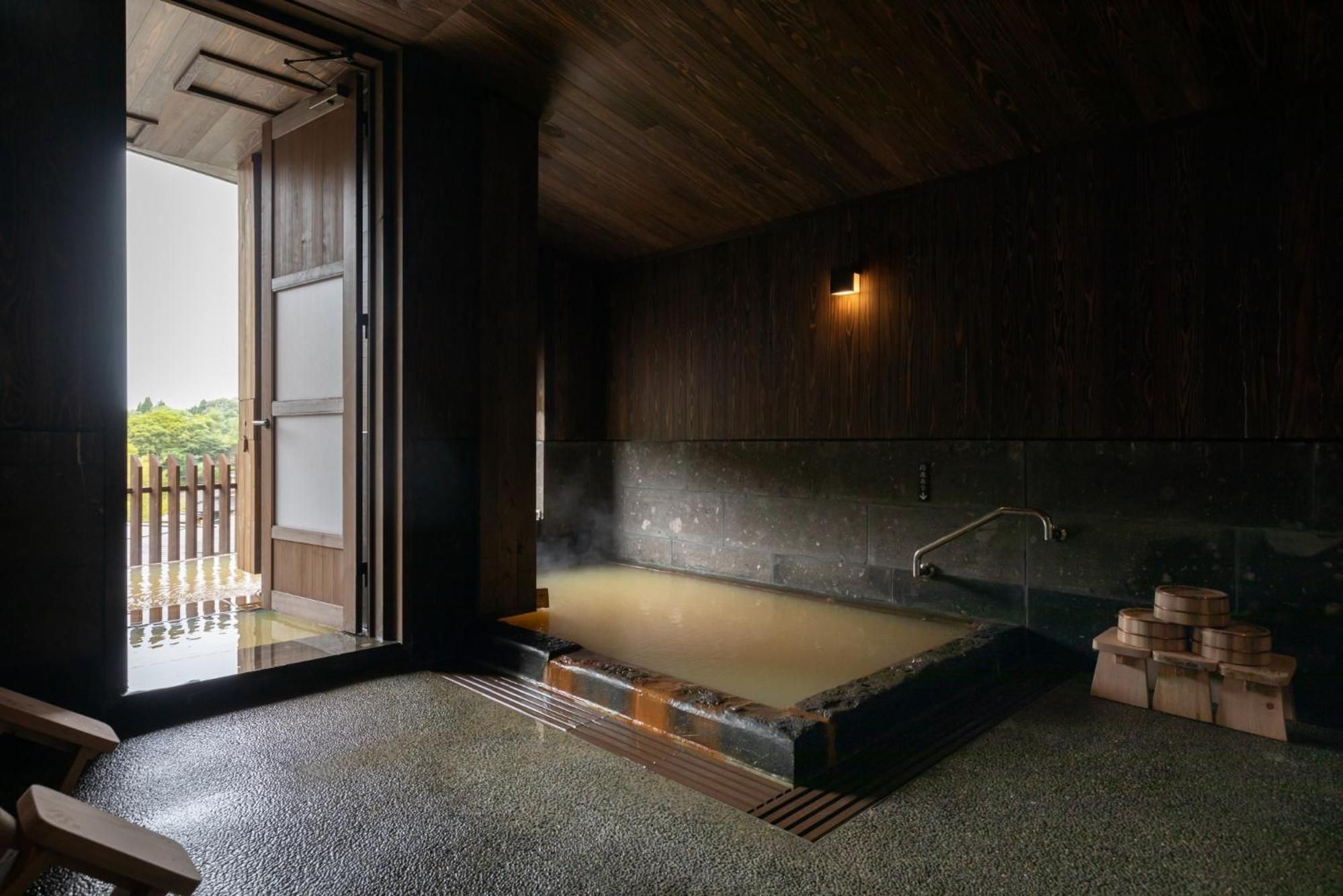 A traditional Japanese onsen with a wooden interior, a hot spring bath, and a wooden bench.