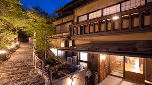 A traditional Japanese building with a stone staircase leading to a wooden deck. - Ryokan Nanjoen (Minamioguni)