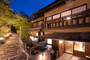 A traditional Japanese building with a stone staircase leading to a wooden deck. - Ryokan Nanjoen (Minamioguni)