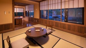 A traditional Japanese room with tatami flooring, a round table with cushions, and sliding doors. - Ryokan Nanjoen (Minamioguni)