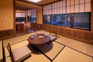 A traditional Japanese room with tatami flooring, a round table with cushions, and sliding doors.