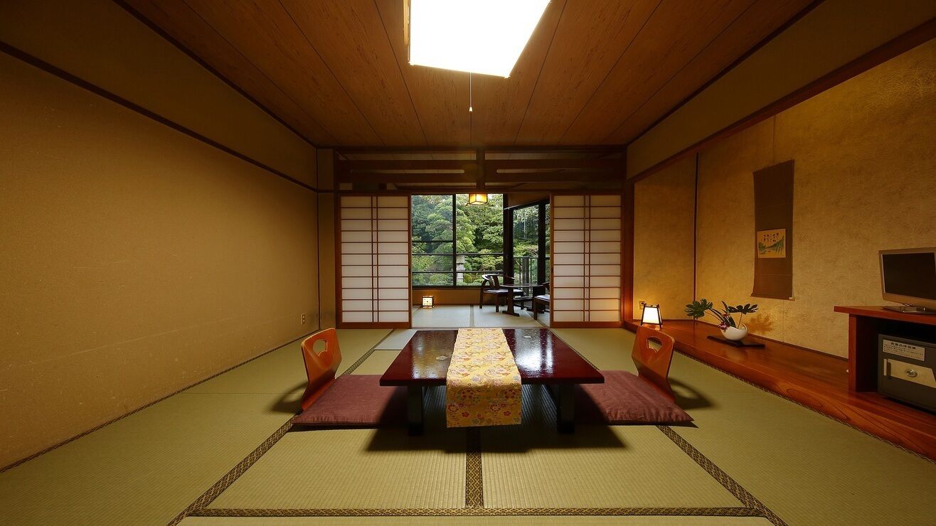 Una stanza tradizionale giapponese con pavimenti in tatami, un tavolino basso e porte scorrevoli.