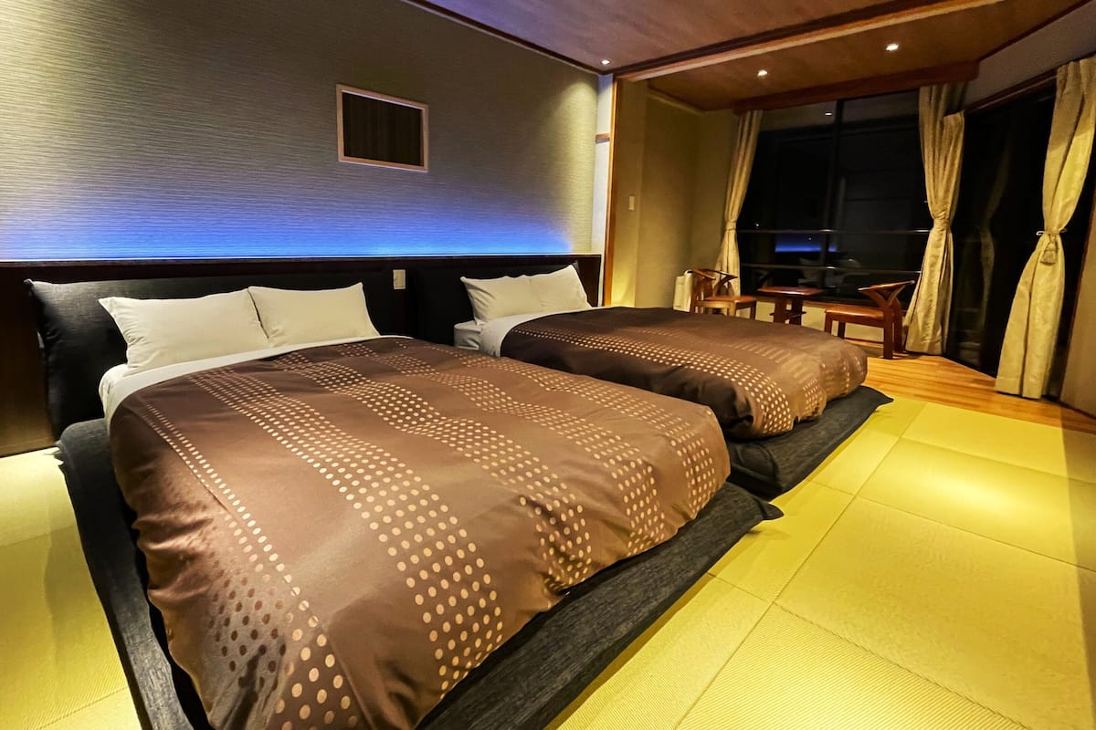 A hotel room with two beds, a small window, and a view of the outside.
