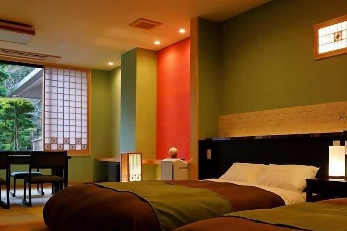 A hotel room with two beds, a desk, and a chair.