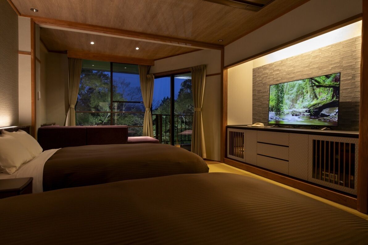 Una camera d'albergo con un letto grande, una televisione e un balcone con tende.