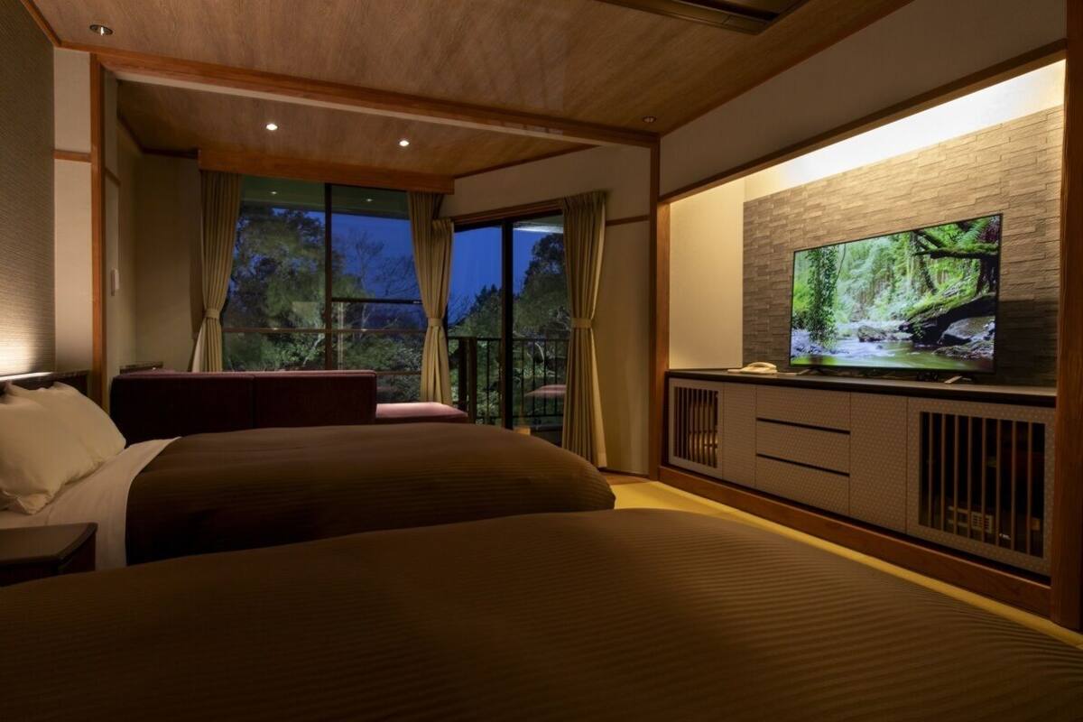 A hotel room with a large bed, a television, and a balcony with curtains.
