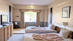 A hotel room with two beds, a television, a desk, and a window with curtains. - Harazuru Onsen Hotel Topmega Itoen (Asakura)