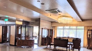 A spacious lobby with a large chandelier, a classic armchair, and a polished floor. - Harazuru Onsen Hotel Topmega Itoen (Asakura)