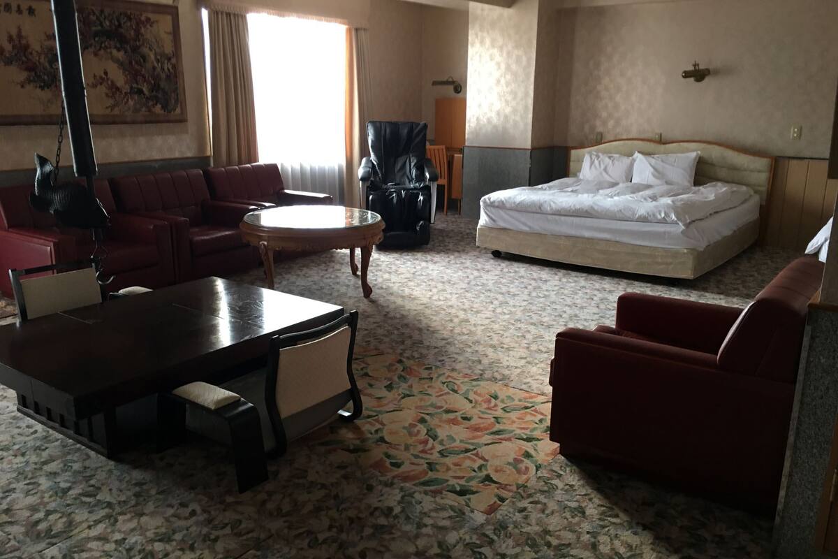 Una habitación de hotel con una cama, un sofá, una mesa de comedor y una silla.