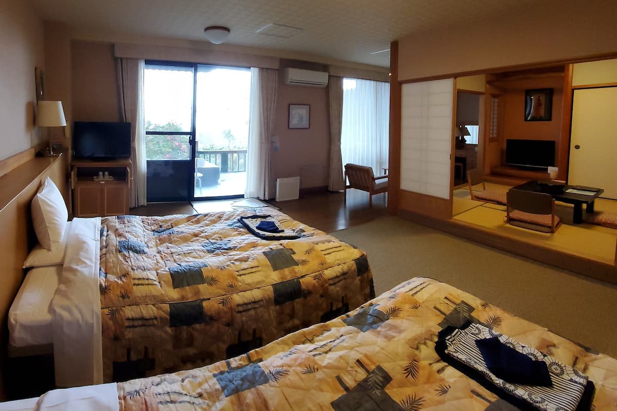 Een hotelkamer met twee bedden, een televisie, een bureau, een stoel en een balkon.