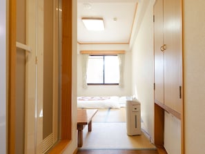 A hotel room with a bed, bedside table, and a heater. - Tabist Business Hotel Fujiya (Sasebo)