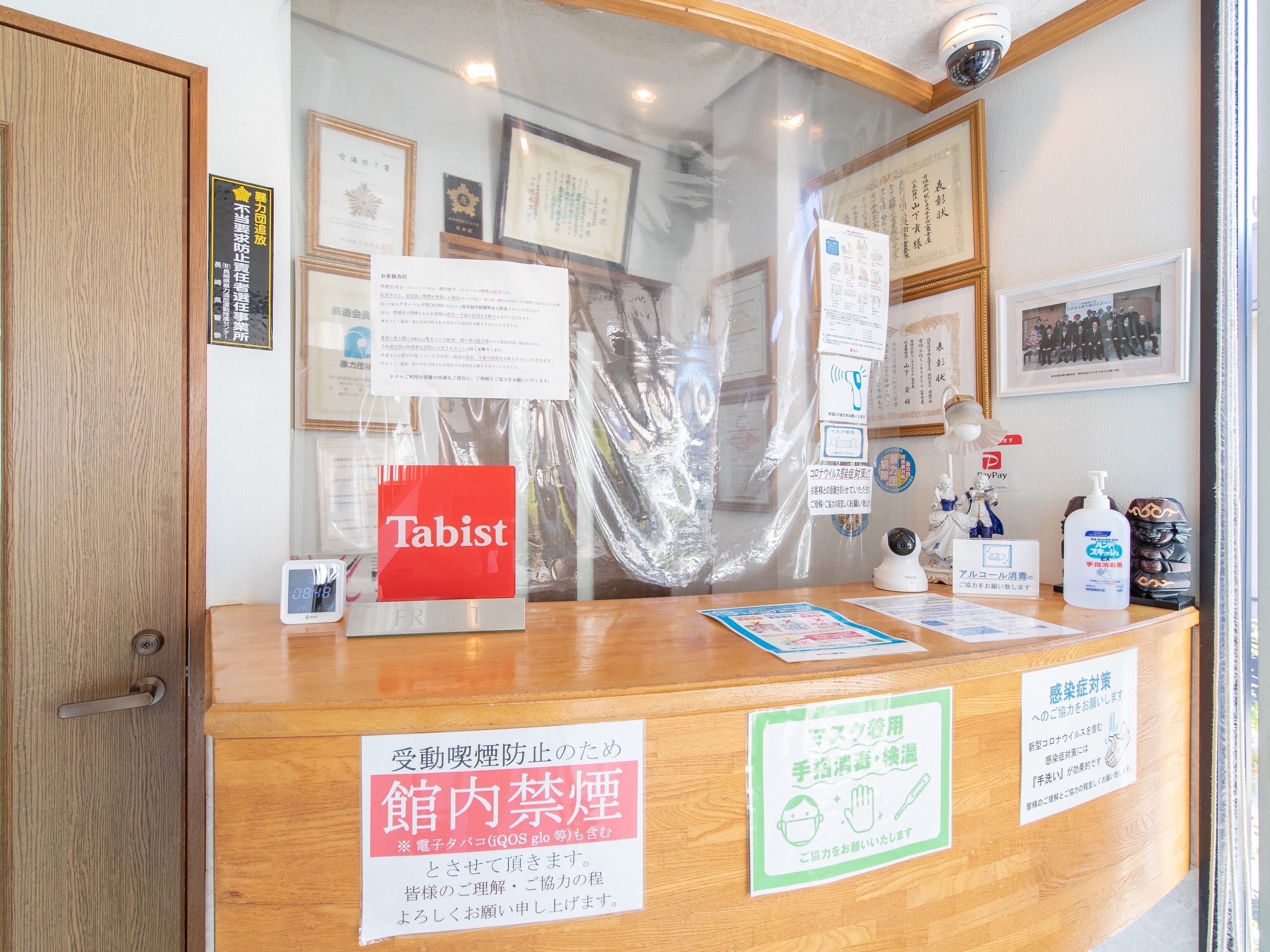 A reception desk with a red 'Tabist' sign, framed certificates, and informational posters.