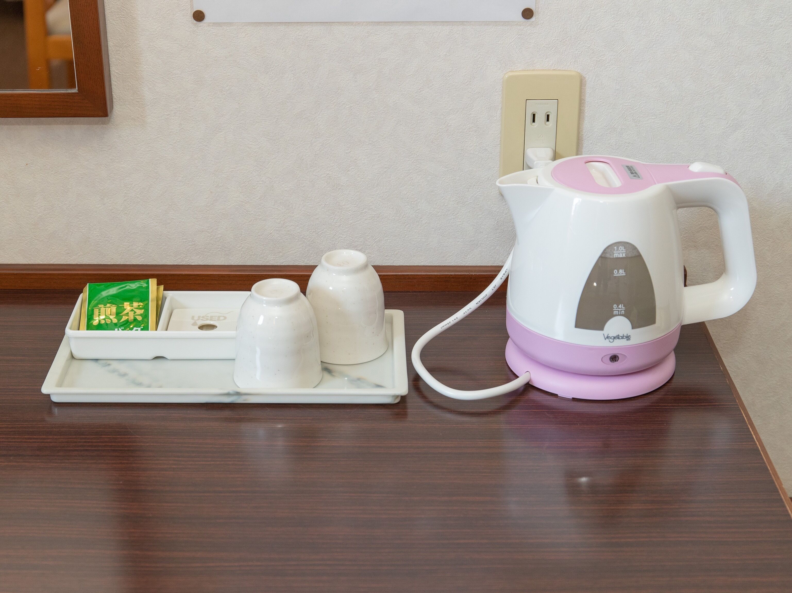 A kitchen area with a kettle, a tray with teapots, and a packet of tea.