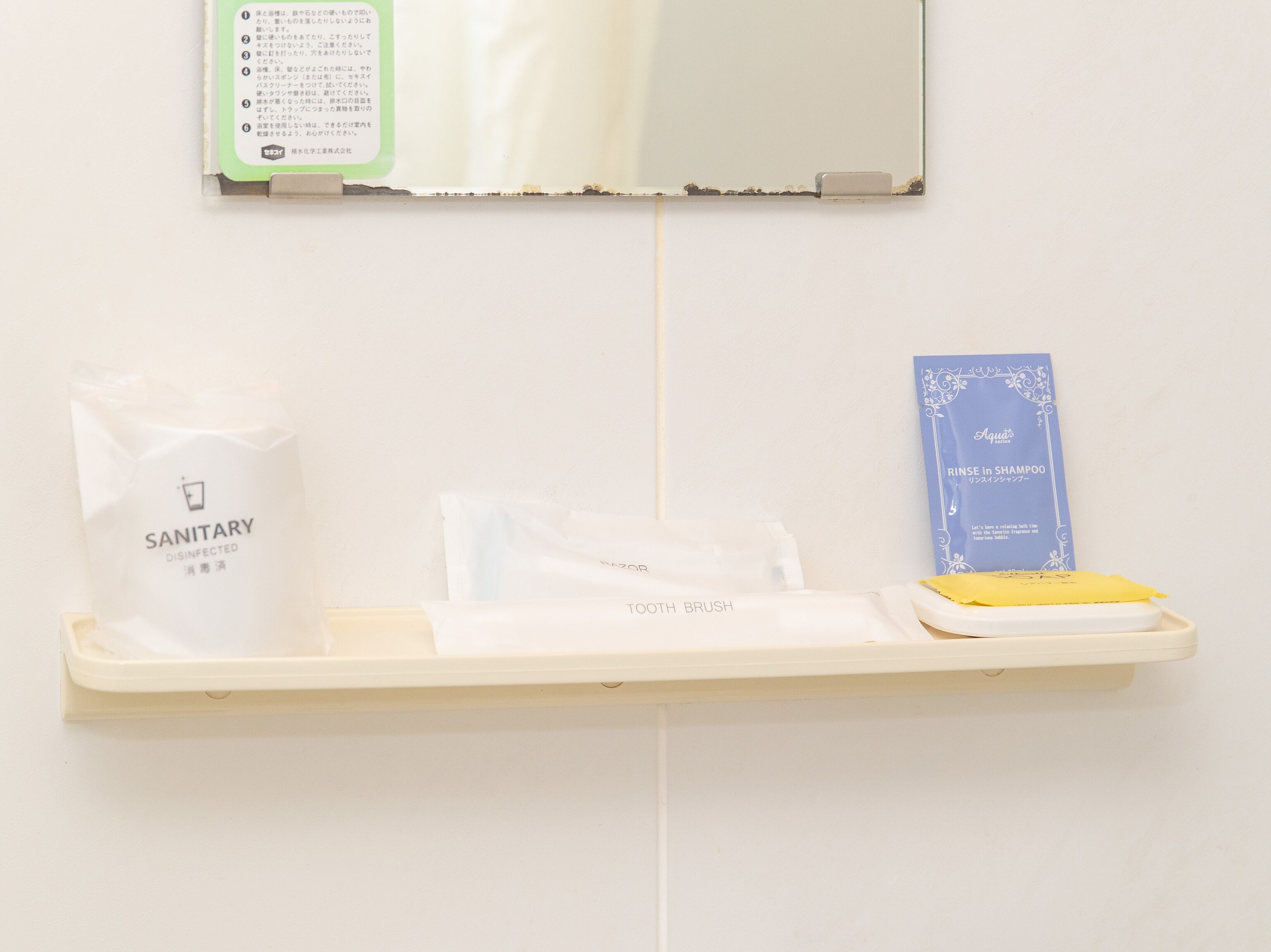 Ein Badezimmerschrank mit einem Hygienebeutel, einer Zahnbürste und einer blauen Schachtel mit japanischen Schriftzeichen.