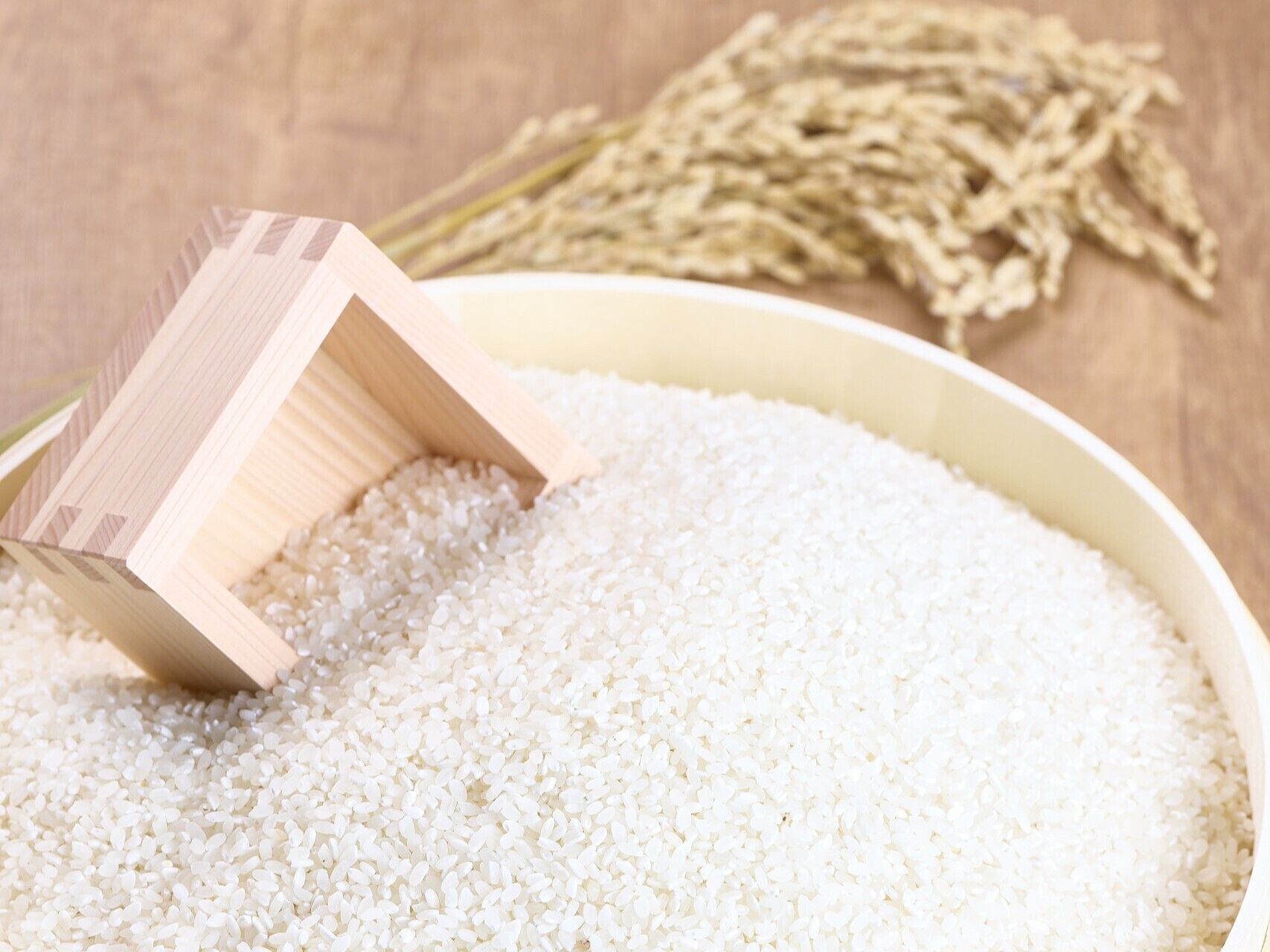 A bowl of white rice with a wooden scoop.