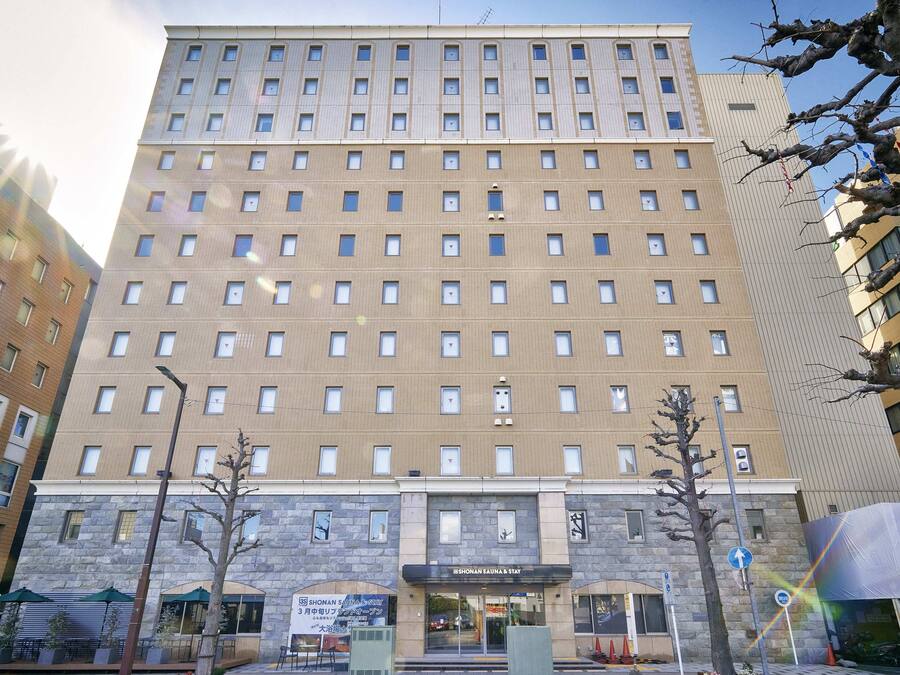 Ein mehrstöckiges Hotel mit Steinaußengebäude, einem zentralen Eingang und einem Schild für "Showa Hotel & Spa".