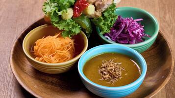 A wooden table with a variety of dishes including shredded carrots, a bowl of soup, and a salad with lettuce and red cabbage.