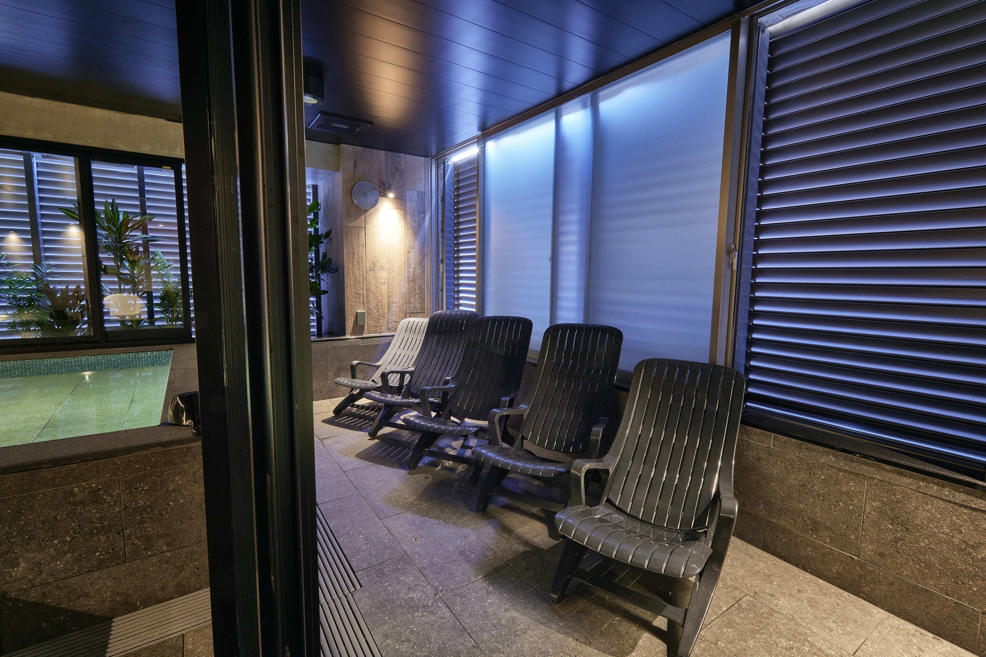A poolside area with lounge chairs, a pool, and a view of the pool.