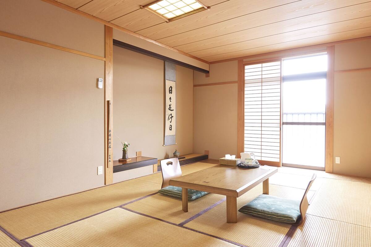 Une pièce de style japonais traditionnel, avec un sol recouvert de tatamis, une basse table en bois et des portes coulissantes en papier de riz (shoji).