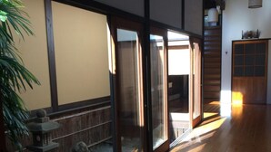 A traditional Japanese interior with sliding doors, a wooden floor, and a small garden area visible through the glass doors. - Temple Stay Tsushima Seizanji (Tsushima)