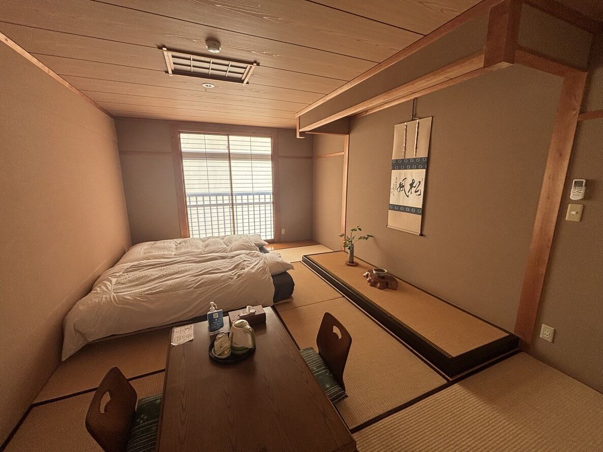 Ett traditionellt japanskt rum med tatamimattor på golvet, en futonmadrass, ett lågt träbord med en vattenkokare och en shojiskärm.