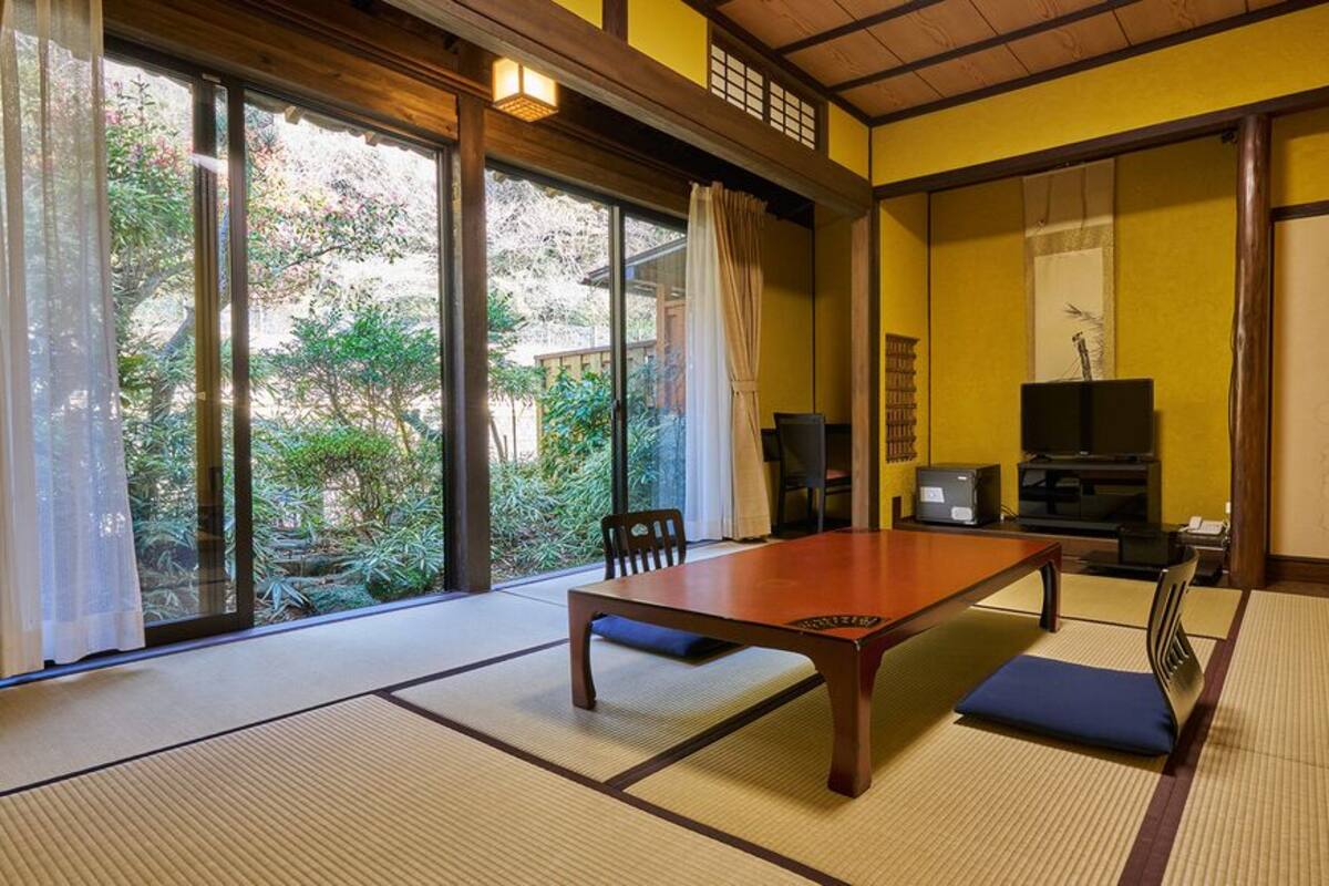 Una habitación japonesa tradicional con suelo de tatami, una mesa baja y puertas correderas.