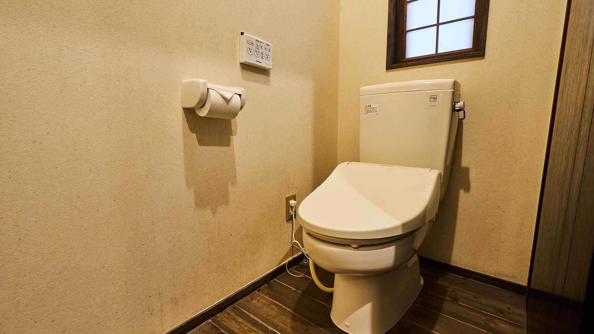 Toilet met tank, toiletpapier en een stopcontact op de muur.