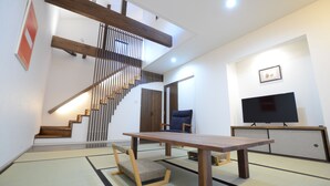 A modern interior with a wooden staircase, tatami flooring, a flat-screen TV, and a dining table. - Yume-hotaru (Amakusa)