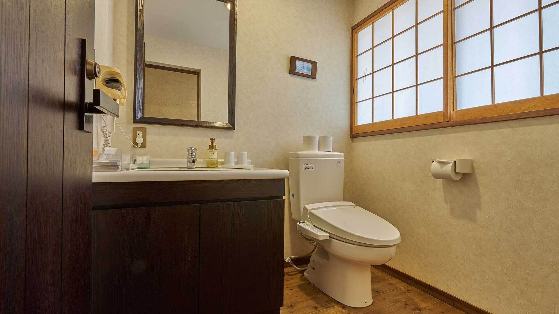 Een badkamer met toilet, wastafel en spiegel.