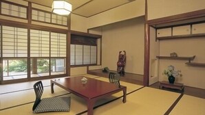 A tatami mat room with a low table, chairs, and a hanging light fixture. - Yume-hotaru (Amakusa)