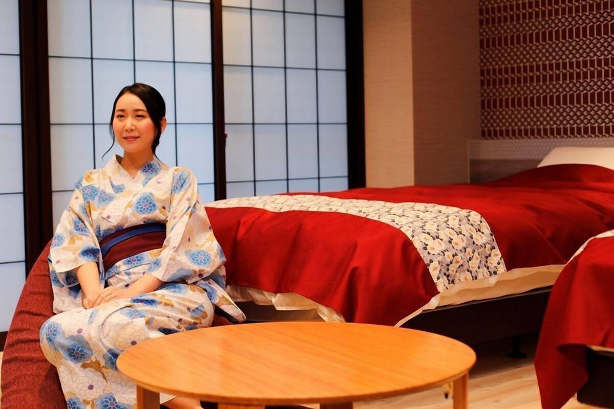 A traditional Japanese room with tatami flooring, a low table, and a bed with red bedding.