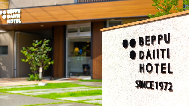 Fasaden på Beppu Daiiti Hotel med en skylt som visar texten: ”Beppu Daiiti Hotel, etablerat 1972”.