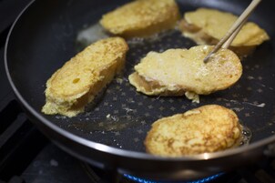 Una sartén con varios panqueques dorados que se cocinan en una estufa.