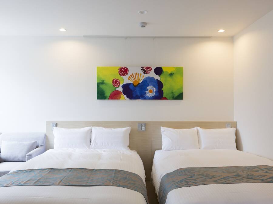 Una habitación de hotel con dos camas, un cuadro en la pared y una lámpara en el techo.