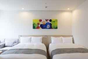 Una habitación de hotel con dos camas, un cuadro en la pared y una lámpara en el techo.