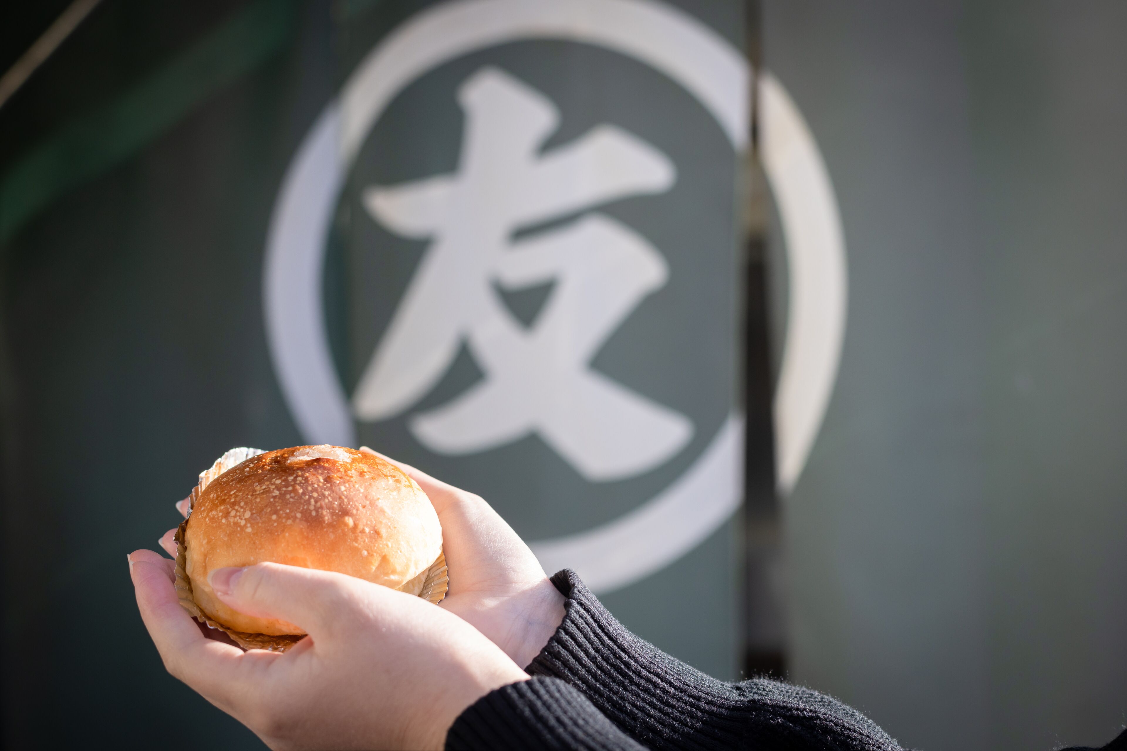 A hand holding a burger with a logo in the background.