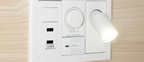 A wall-mounted electrical outlet with a USB port, a power socket, and a light switch.
