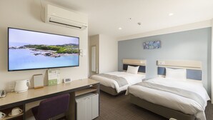Ett hotellrum med TV, skrivbord, två sängar, ett litet kylskåp och en stol.