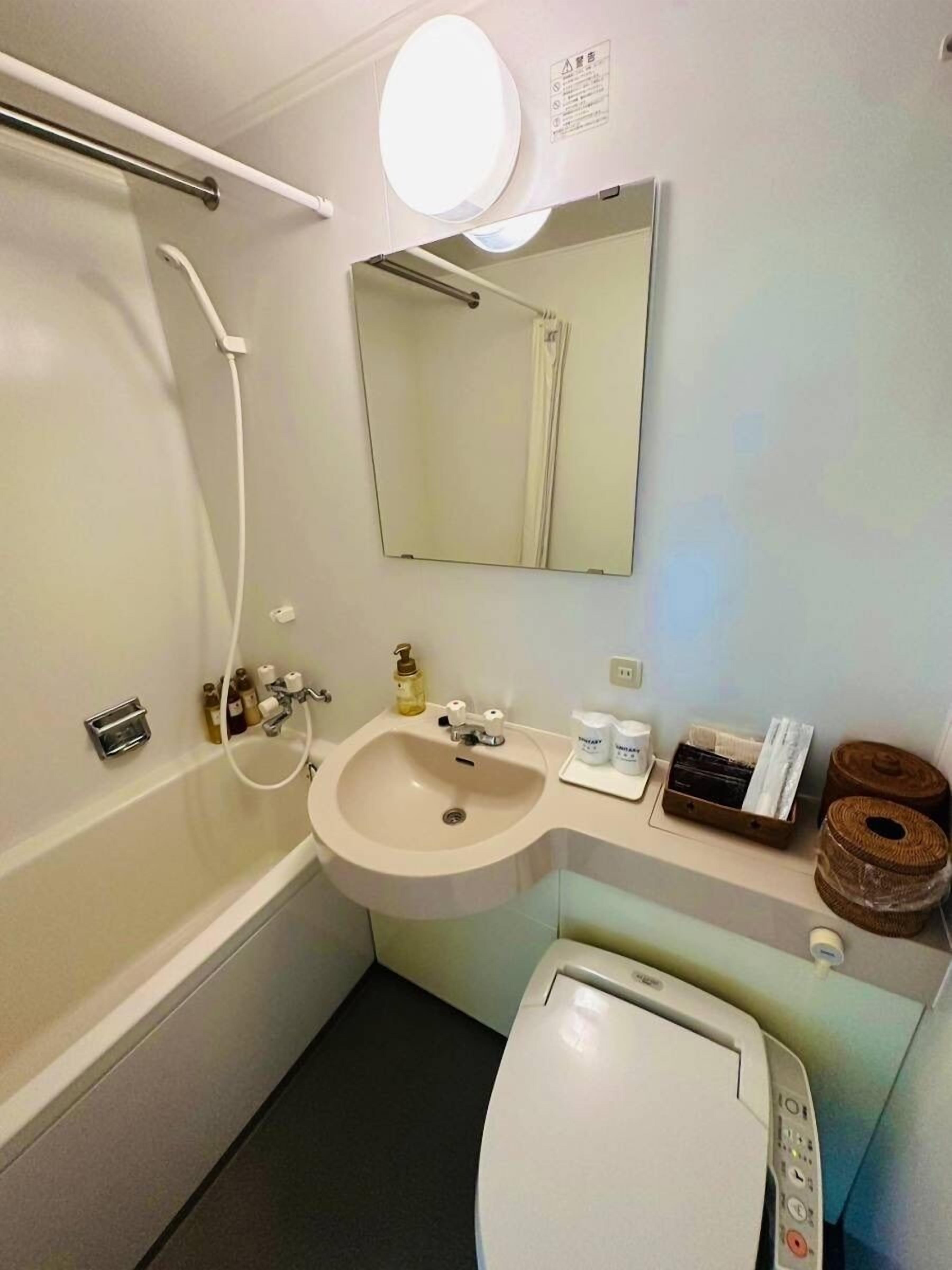 Un bany amb banyera, un lavabo, un vàter, un mirall i una barra de tovalloles.