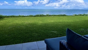 A grassy lawn with a view of the ocean and a chair. - Eco Village Iriomote (Taketomi)
