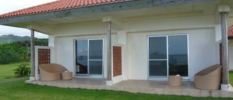 Una casa moderna con un porche cubierto, grandes puertas correderas de vidrio y techo plano.
