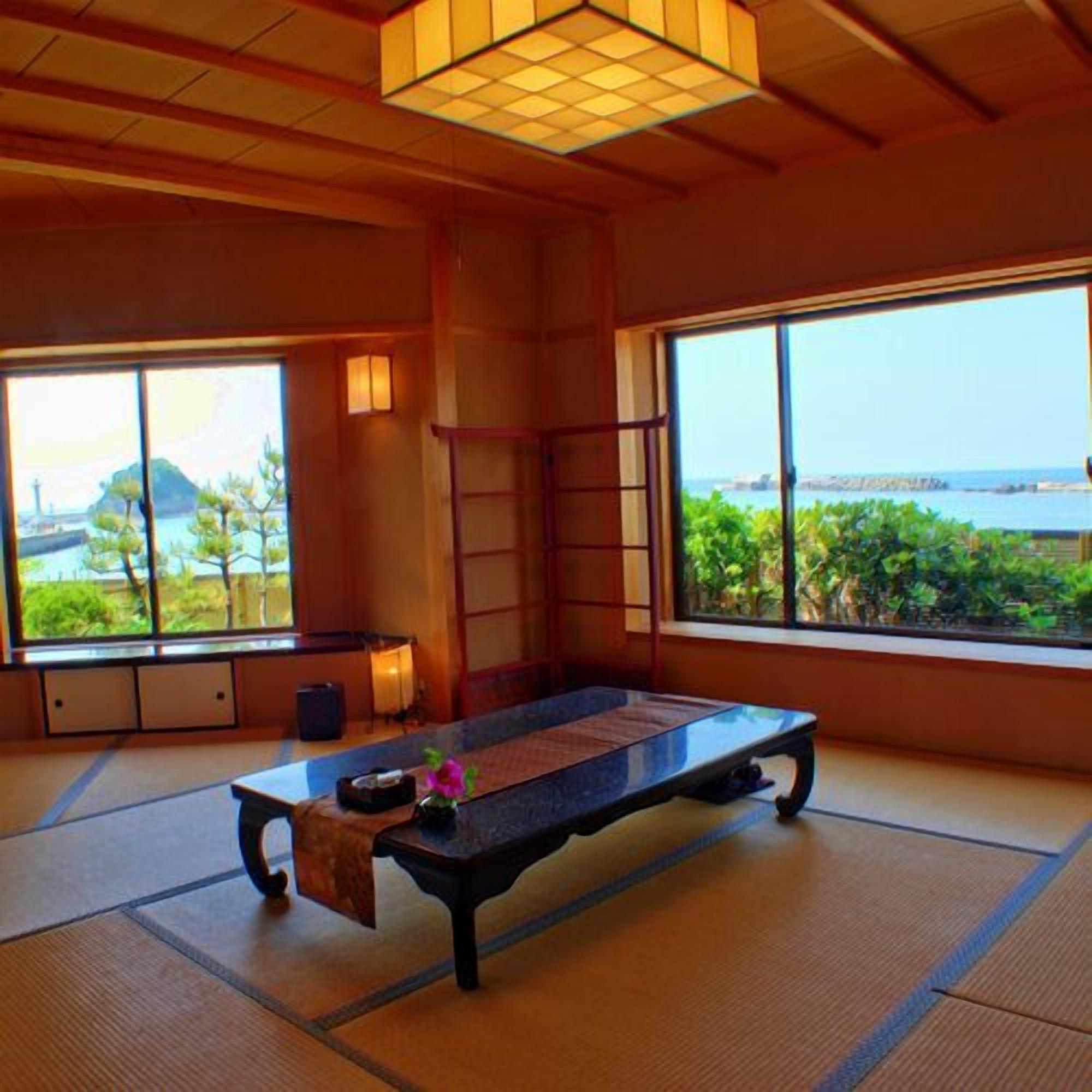 A tatami mat room with a low table, a ladder, and a view of the sea.