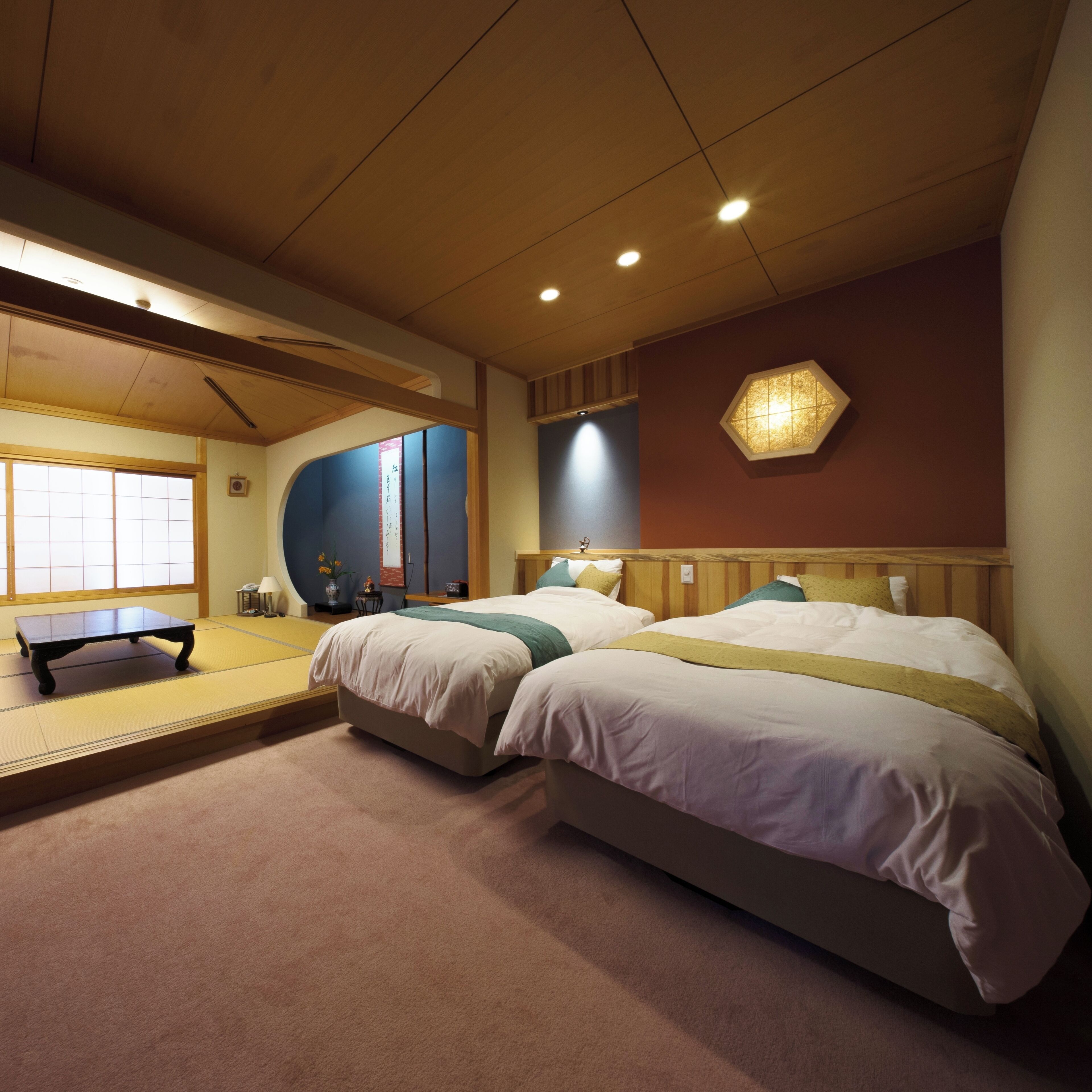 A room with two beds, a tatami mat, a small table, and a traditional Japanese-style window.