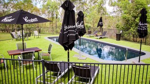 Un espace aménagé au bord de la piscine, avec des chaises longues, des parasols et une petite piscine.
