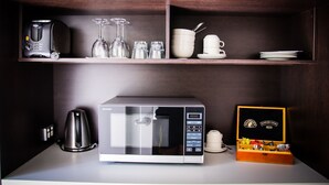 Un coin cuisine équipé d’un four à micro-ondes, d’une machine à café et d’une boîte de sachets de thé.