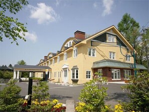 A yellow building with multiple windows and a covered entrance.