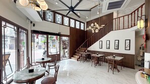 A spacious interior with a high ceiling, large windows, and a staircase leading to an upper level. - Loftel 22 Hostel (Bangkok)